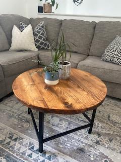 Round stained wood coffee table with black metal legs